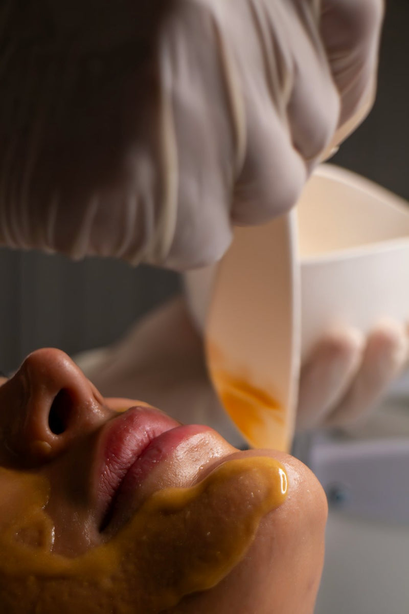 Golden botanical mask during the Practical Magic Facial
